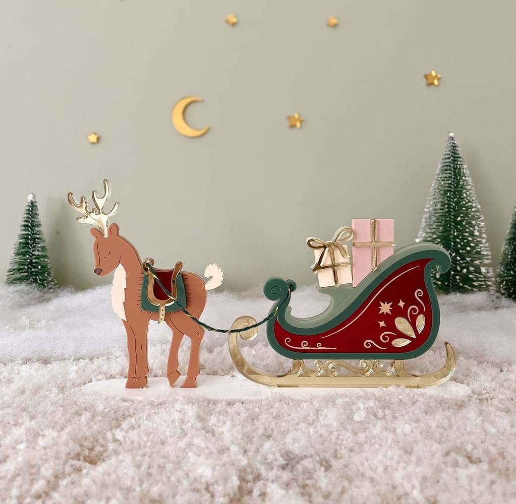 Tra&icirc;neau de No&euml;l en bois tir&eacute; par un renne et charg&eacute; de cadeaux, sous un ciel &eacute;toil&eacute;